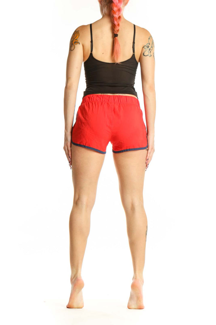 Red Adidas athletic shorts with navy trim, back view on model, showing fit and design