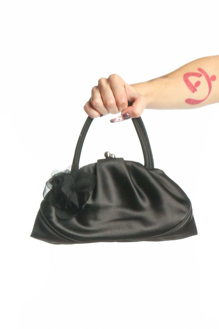 Black satin ruched clutch with dual handles held by hand, showing gathered texture and elegant design