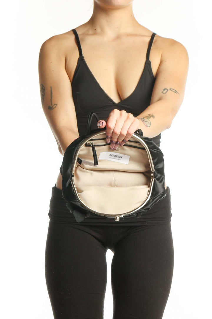 Black satin ruched clutch worn as shoulder bag, displaying the sophisticated gathered silhouette and refined styling