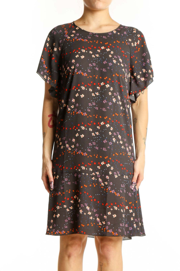 Black floral short sleeve Cabi dress with red, orange, and cream scattered blooms, front view on model