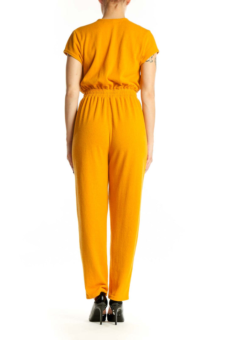 Gold deep V-neck short sleeve jumpsuit with elasticized waist and side pockets, back view