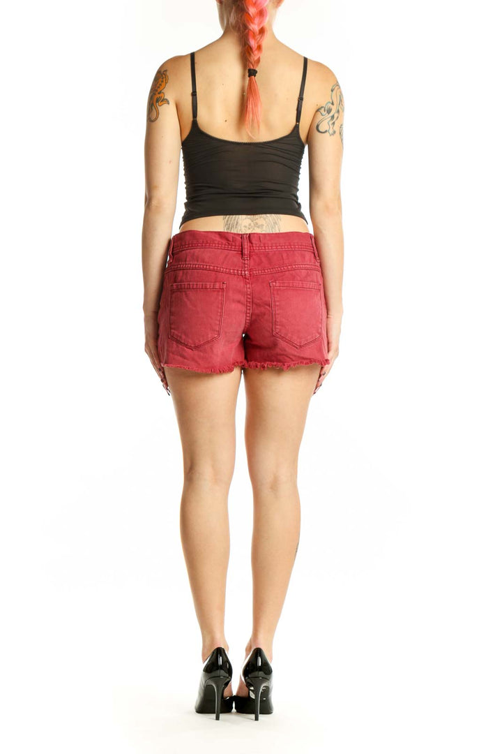 Red distressed cotton denim shorts with frayed edges, back view on model