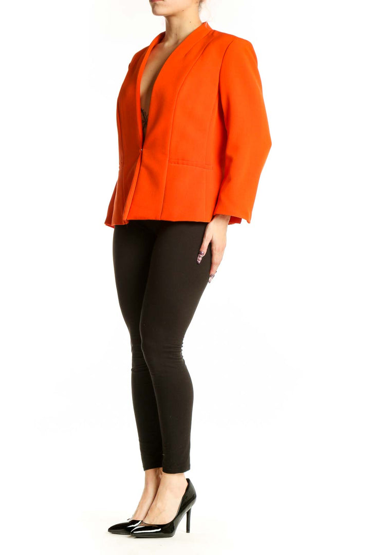 Orange blazer with peplum hem and long sleeves, front view on model wearing black pants