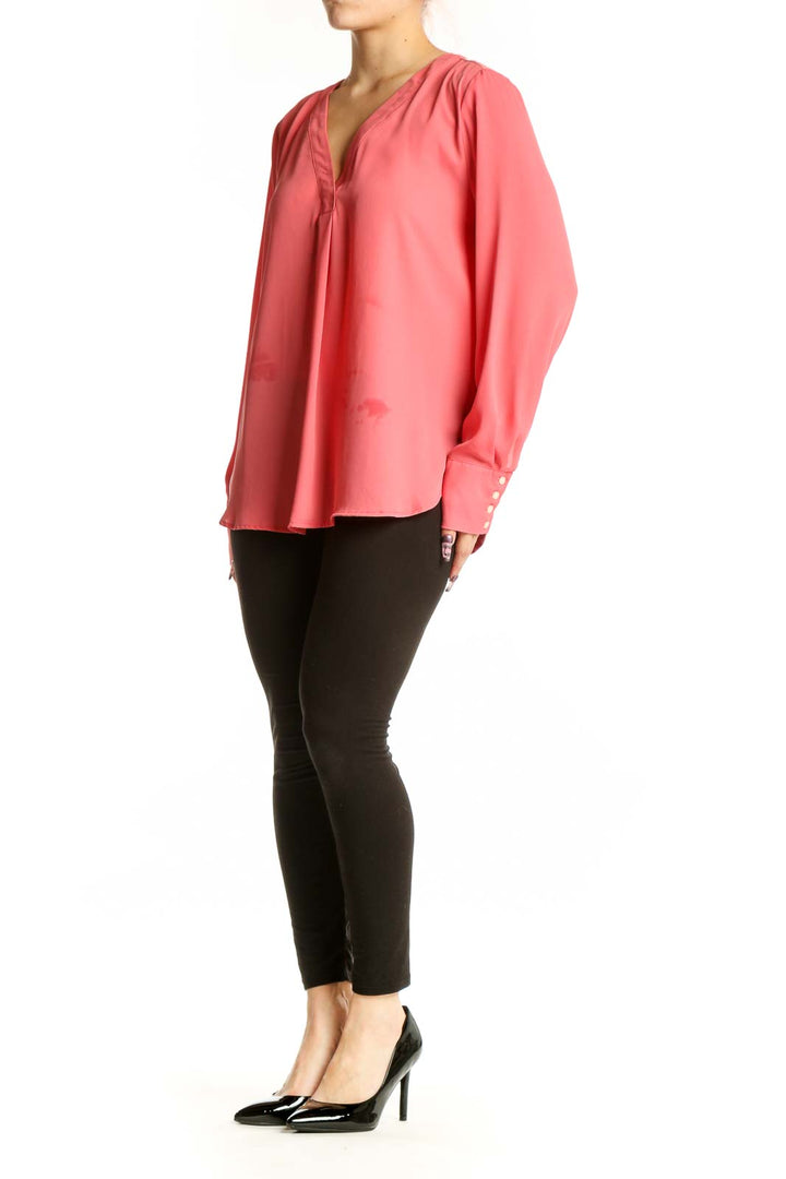 Coral pink V-neck long sleeve blouse by Ann Taylor with button cuff details, front view on model