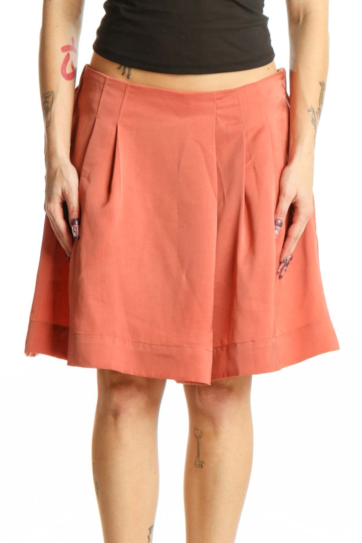 Coral pleated knee-length shorts from Banana Republic, front view showing waist pleating and solid color design