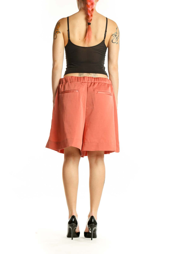 Coral pleated knee-length shorts from Banana Republic, back view displaying the elegant silhouette and fit