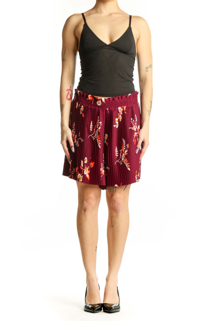 Front view of burgundy floral pleated shorts with orange and yellow botanical print, elastic waistband, and knee-length cut