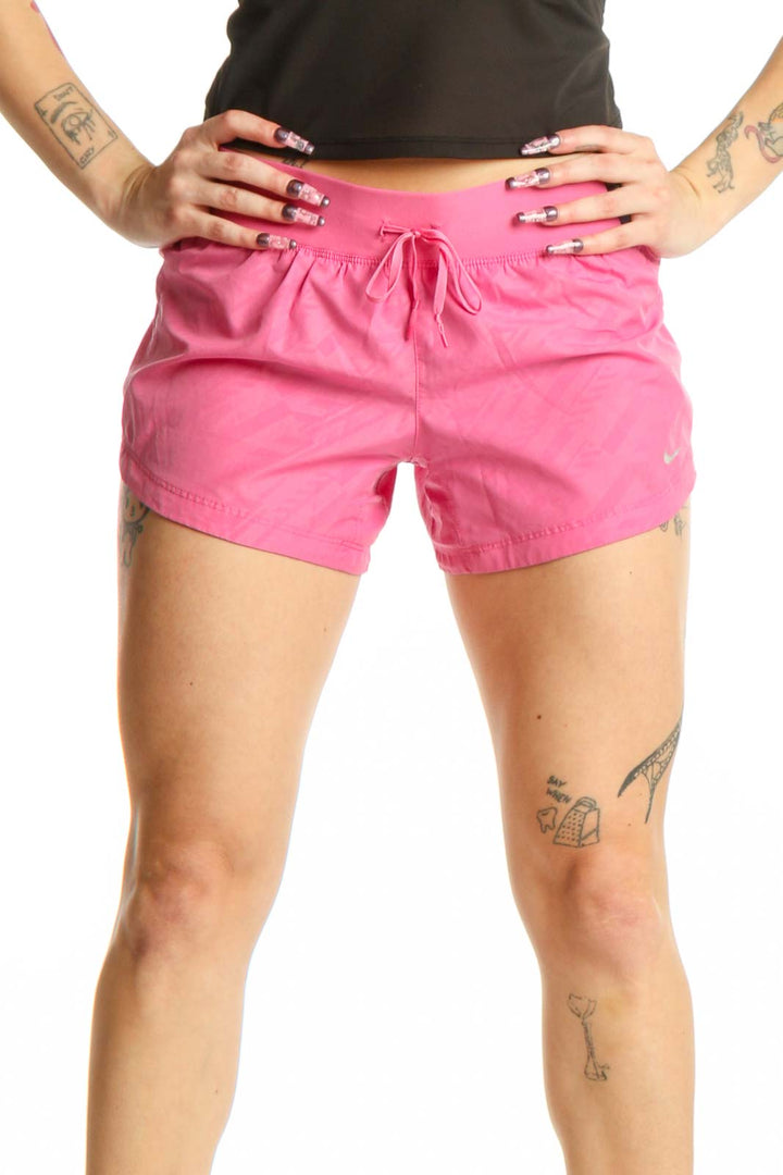Front view of pink Nike athletic shorts with drawstring waist and Nike Swoosh logo