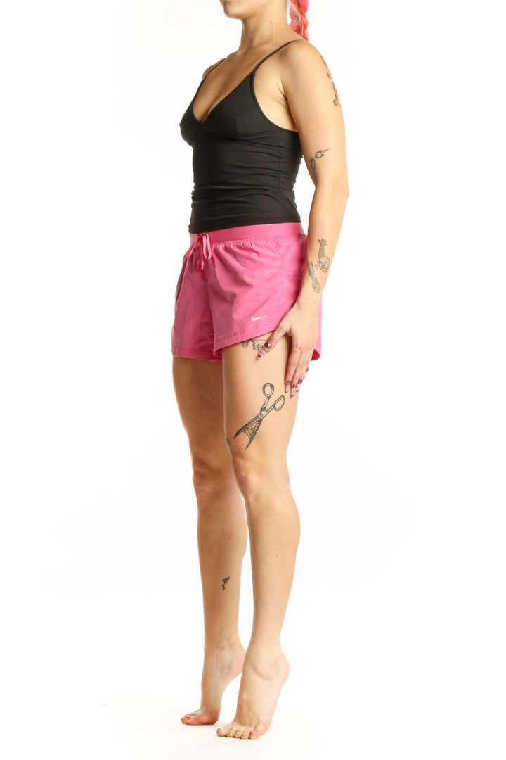 Front view of pink Nike athletic shorts with drawstring waist and Nike Swoosh logo