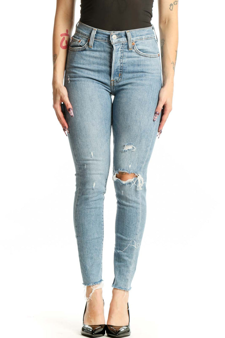 Light blue Levi's distressed skinny jeans front view, high-waisted with ripped thigh detailing, worn with black top