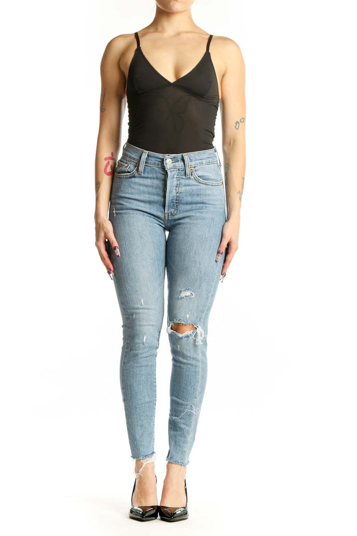 Light blue Levi's distressed skinny jeans front view, high-waisted with ripped thigh detailing, worn with black top