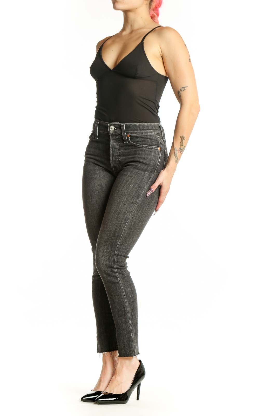 Front view of gray cropped skinny Levi's jeans with distressed hem on model wearing black top