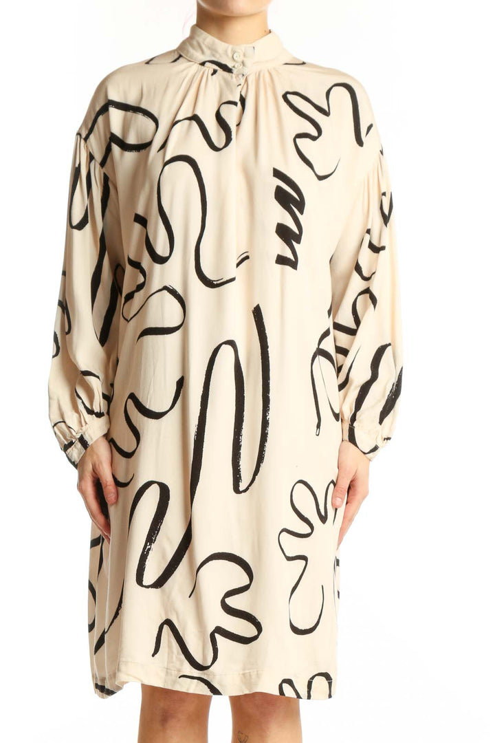 Front view of cream viscose shift dress with black abstract line print, long sleeves, and tie-neck detail