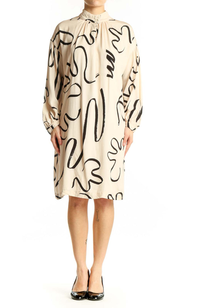 Front view of cream viscose shift dress with black abstract line print, long sleeves, and tie-neck detail