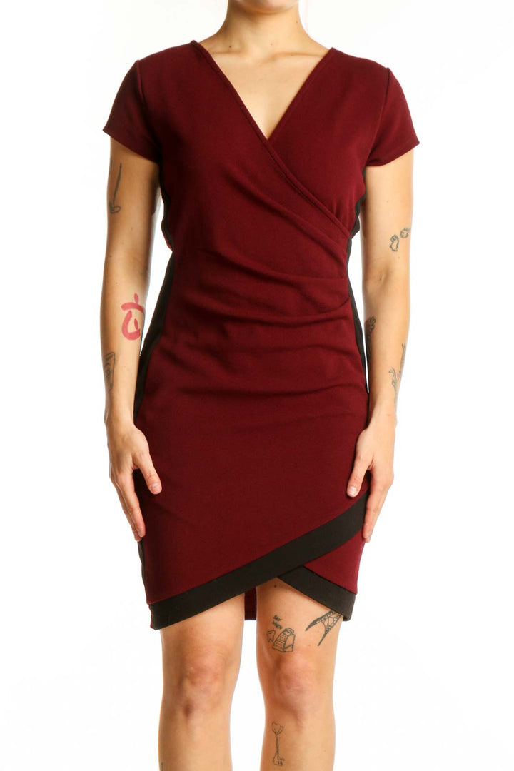 Burgundy wrap short sleeve dress with black asymmetrical trim and ruched bodice, front view