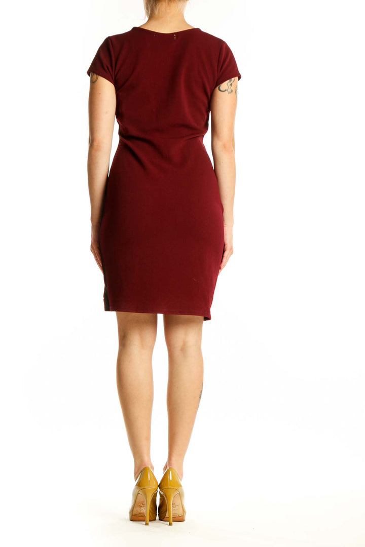 Burgundy wrap short sleeve dress with black asymmetrical trim detail, back view