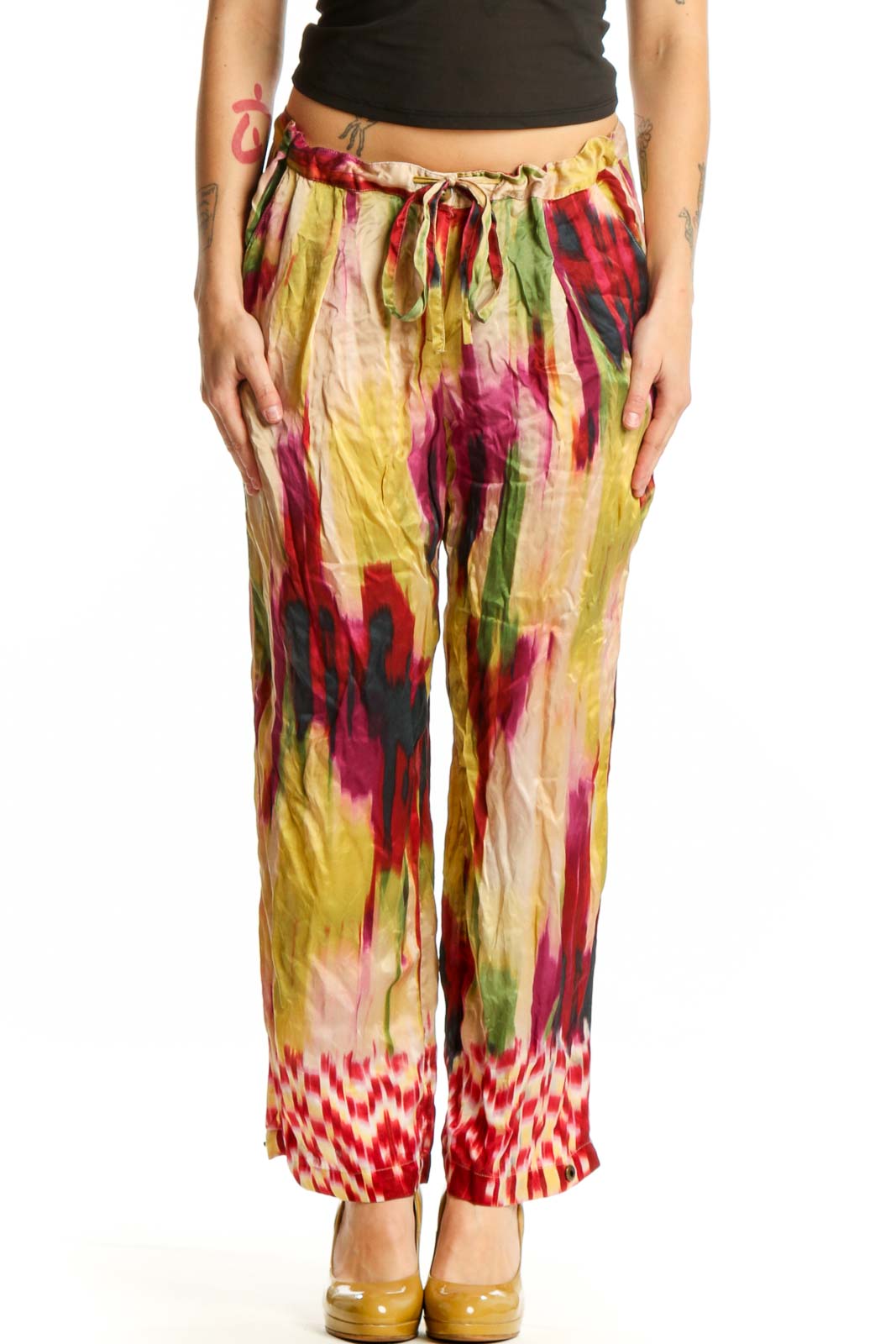 Front view of multicolor silk ikat print pants with vibrant red, yellow, pink, and green watercolor pattern and geometric hem detail