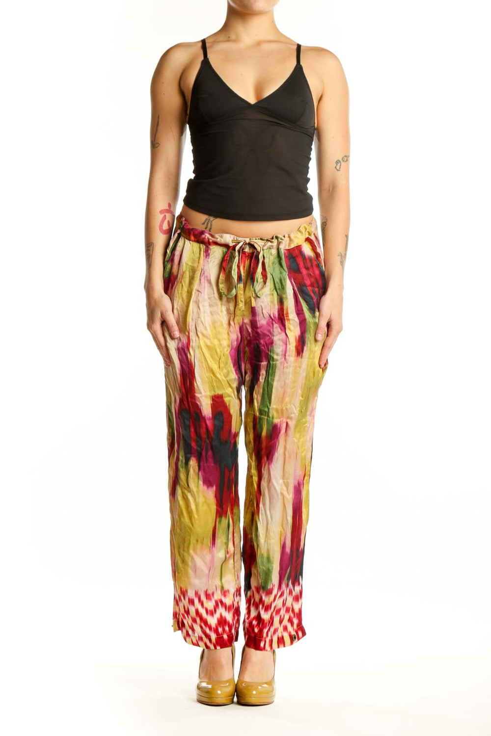 Front view of multicolor silk ikat print pants with vibrant red, yellow, pink, and green watercolor pattern and geometric hem detail