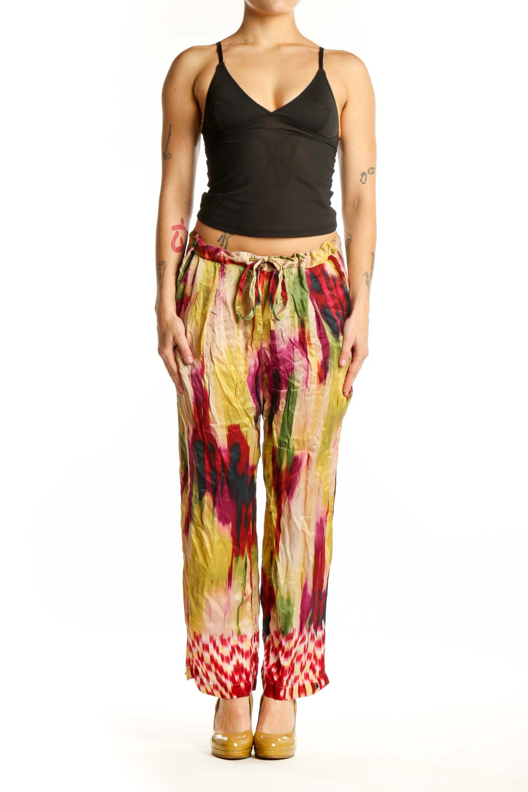 Front view of multicolor silk ikat print pants with vibrant red, yellow, pink, and green watercolor pattern and geometric hem detail