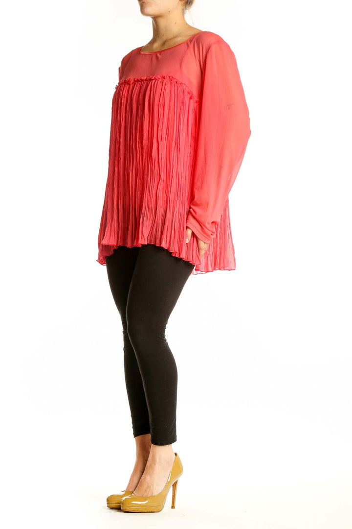 Red pleated long sleeve top with A-line silhouette and flowing pleated front detail