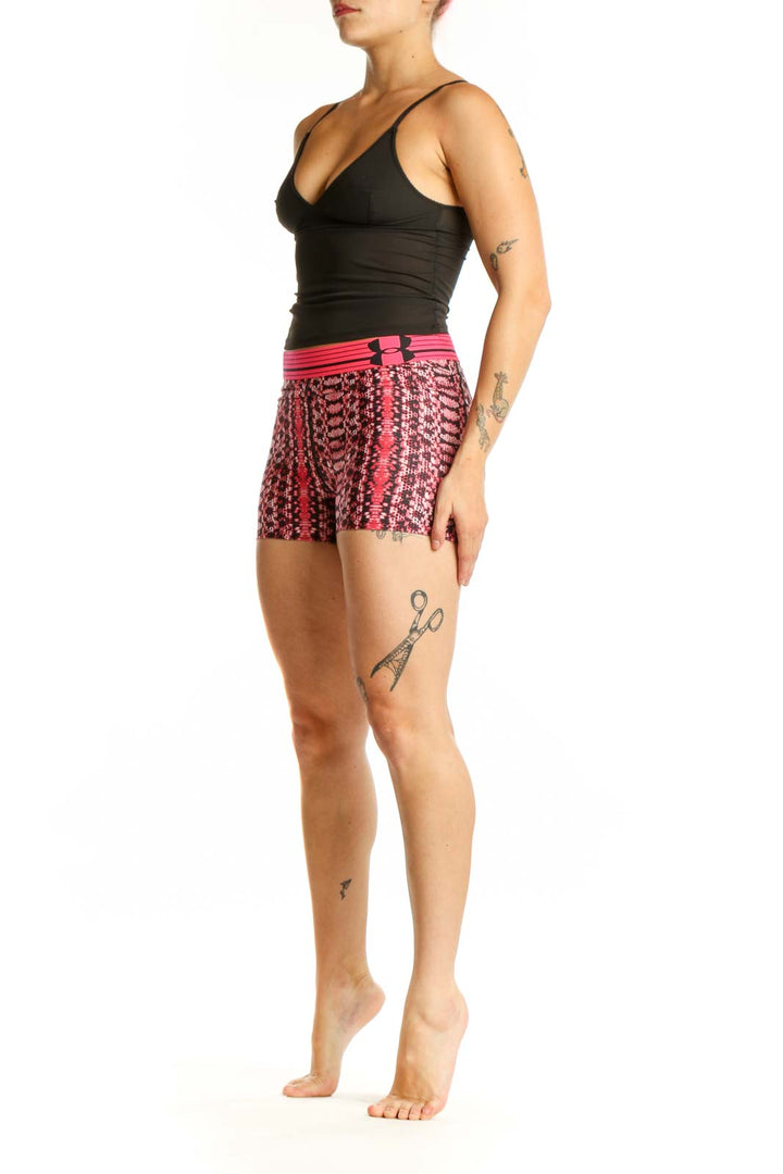 Front view of pink geometric print Under Armour athletic shorts with pink waistband on model