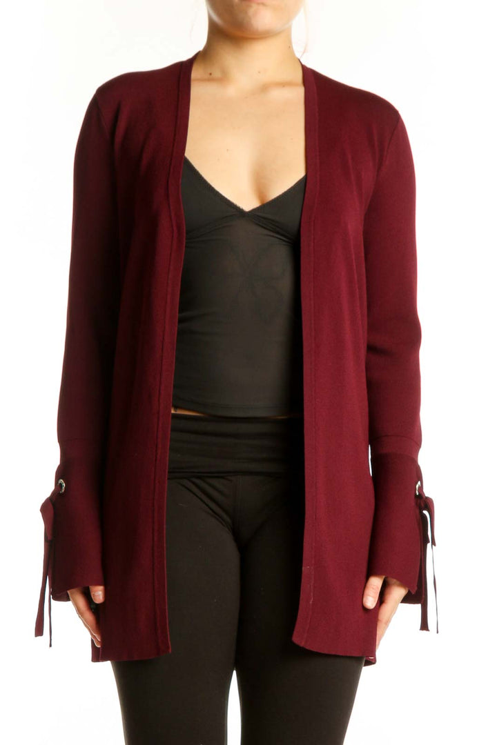 Burgundy open front cardigan with tie-detail cuffs worn over black top, front view