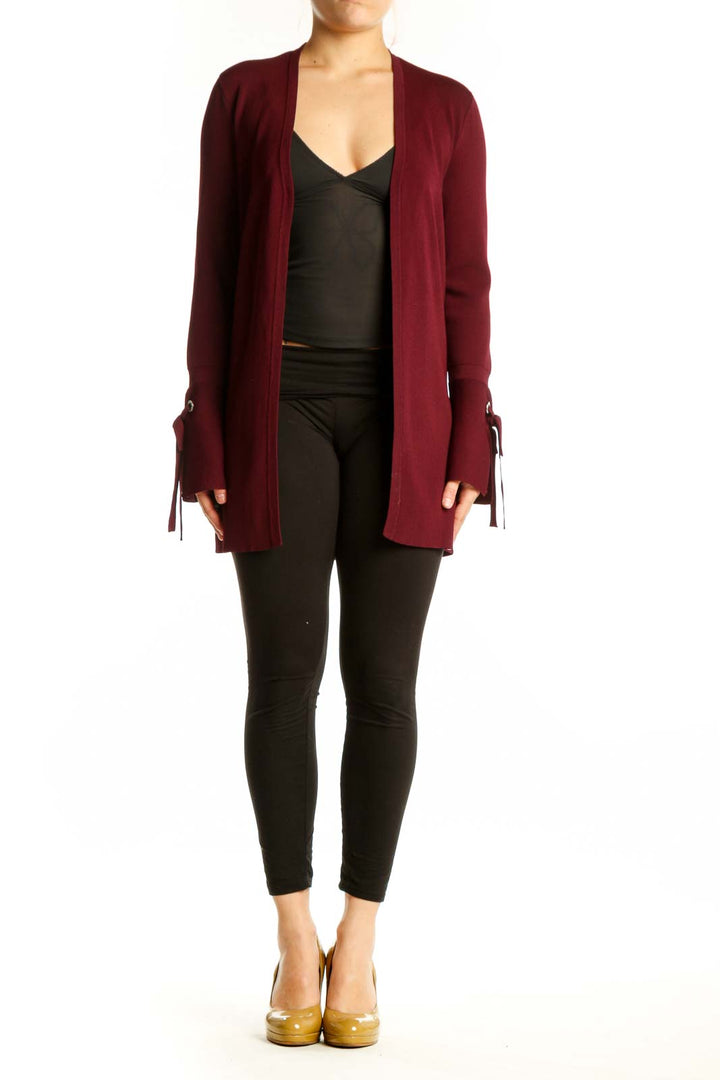 Burgundy open front cardigan with tie-detail cuffs worn over black top, front view