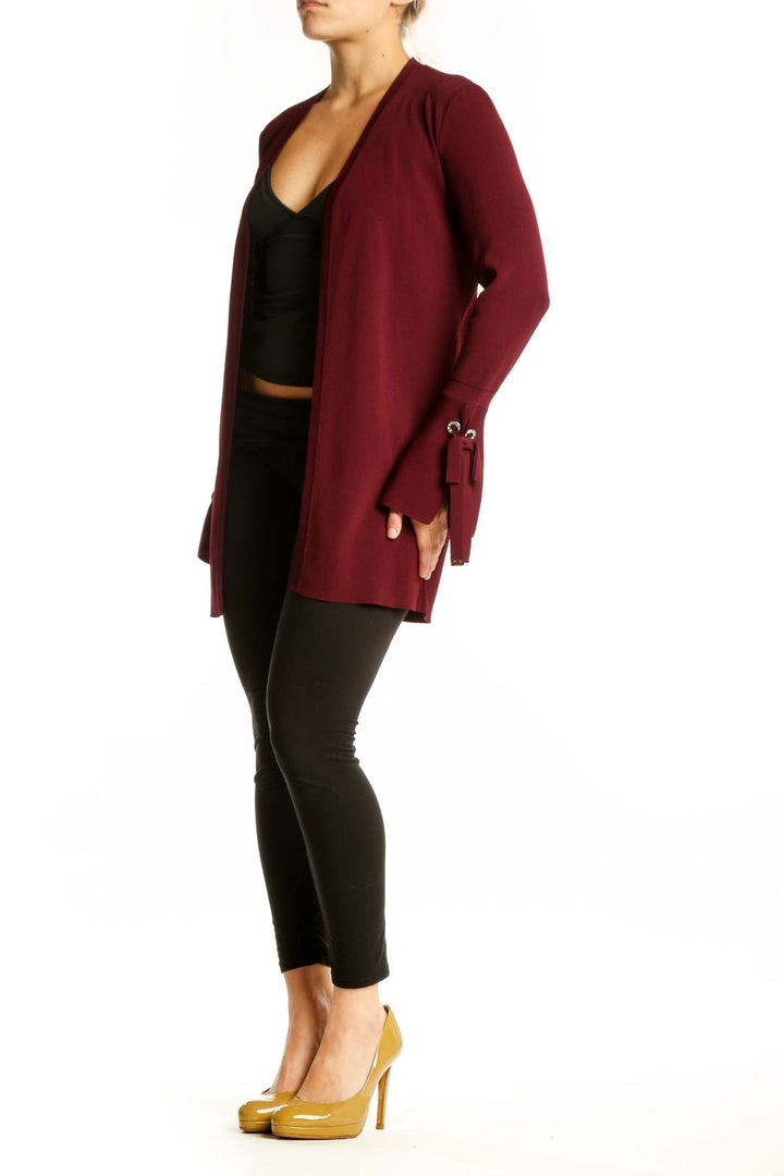 Burgundy open front cardigan with tie-detail cuffs worn over black top, front view