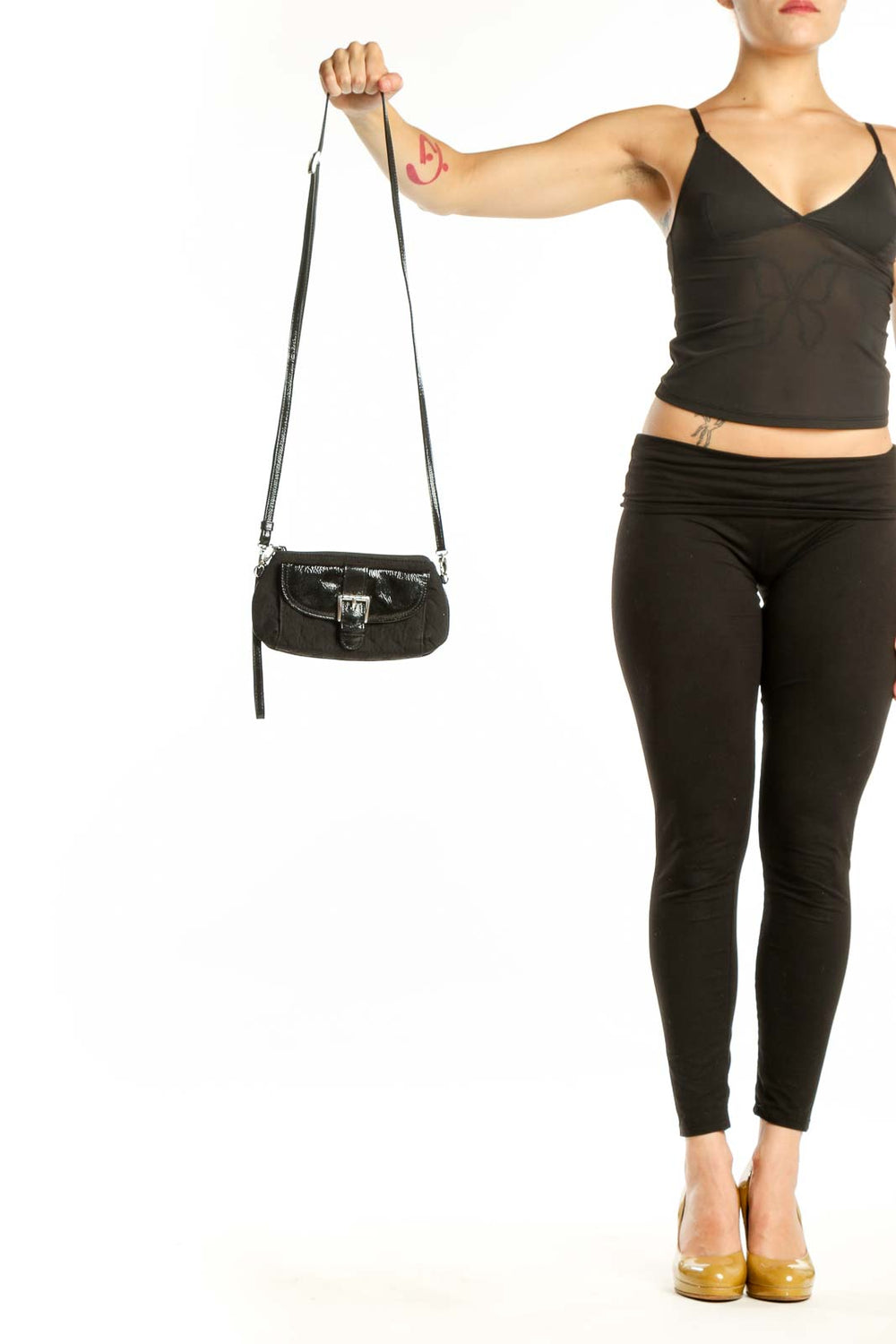 Black leather crossbody bag by Brighton with adjustable strap held in hand, showing front flap closure and silver hardware