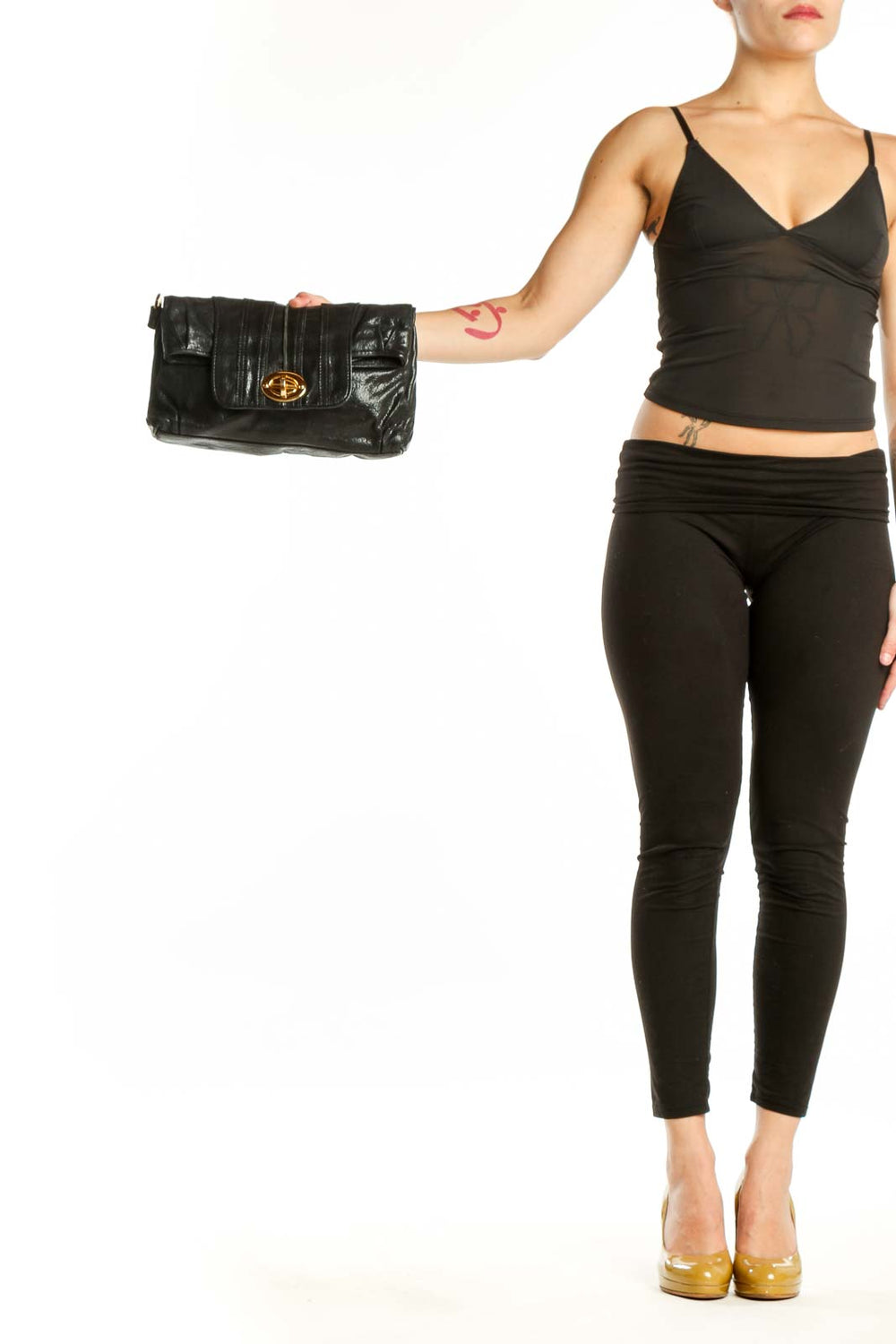 Black quilted leather clutch with gold-tone turnlock closure held in hand