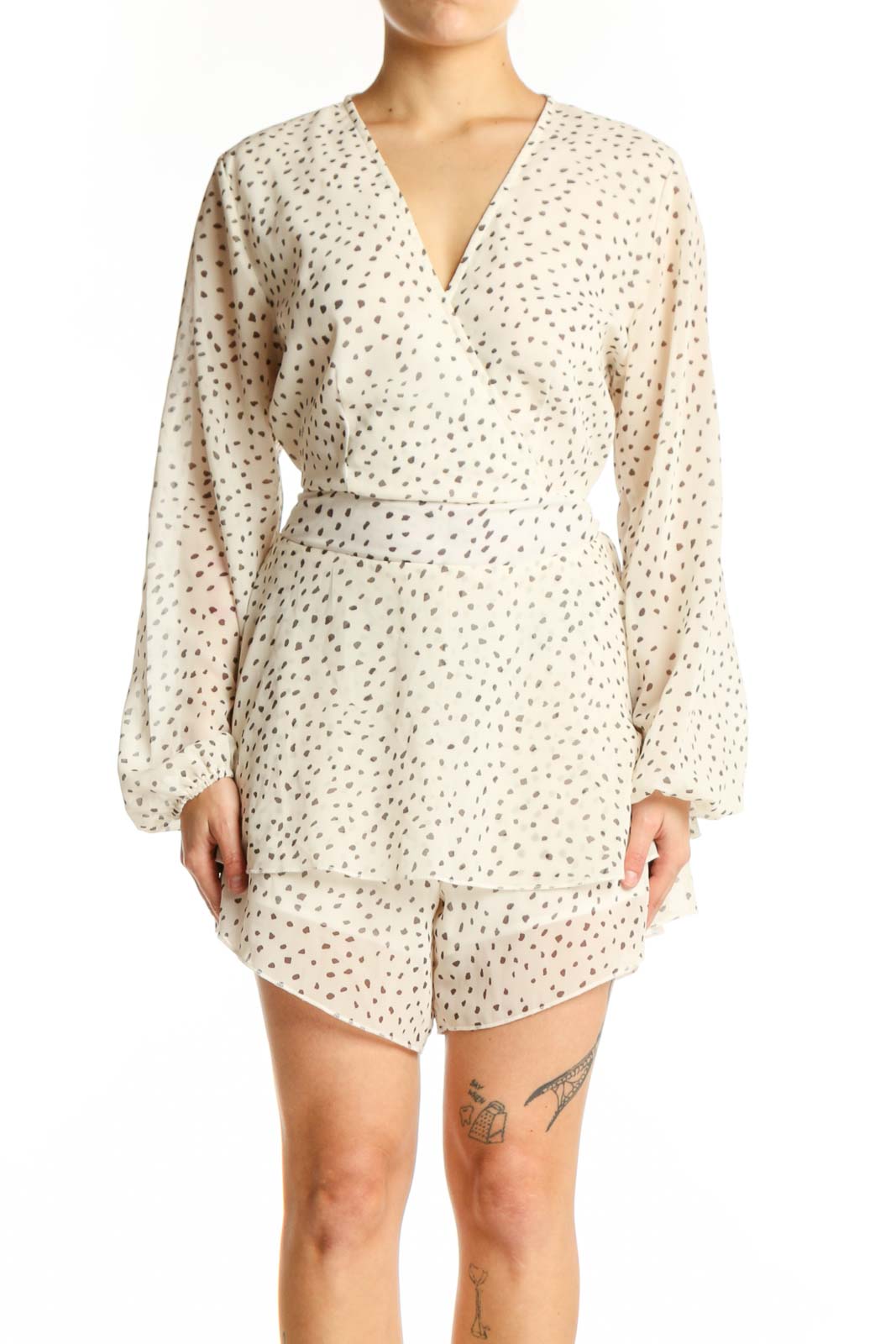 Front view of cream polka dot wrap romper with long sleeves and tiered ruffle hem