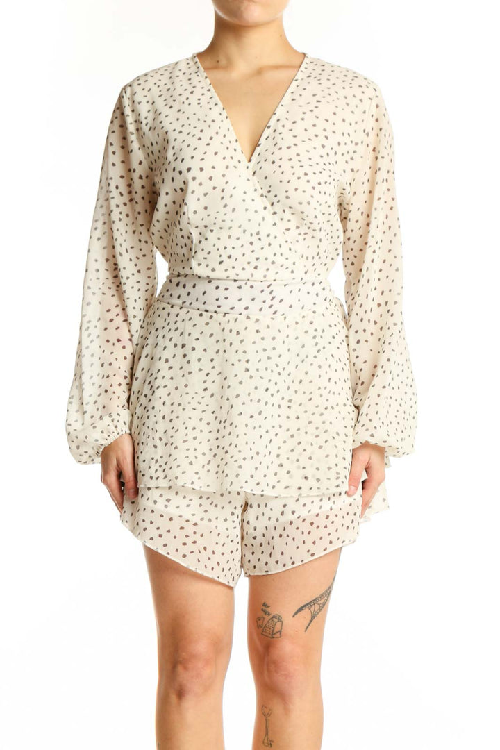 Front view of cream polka dot wrap romper with long sleeves and tiered ruffle hem