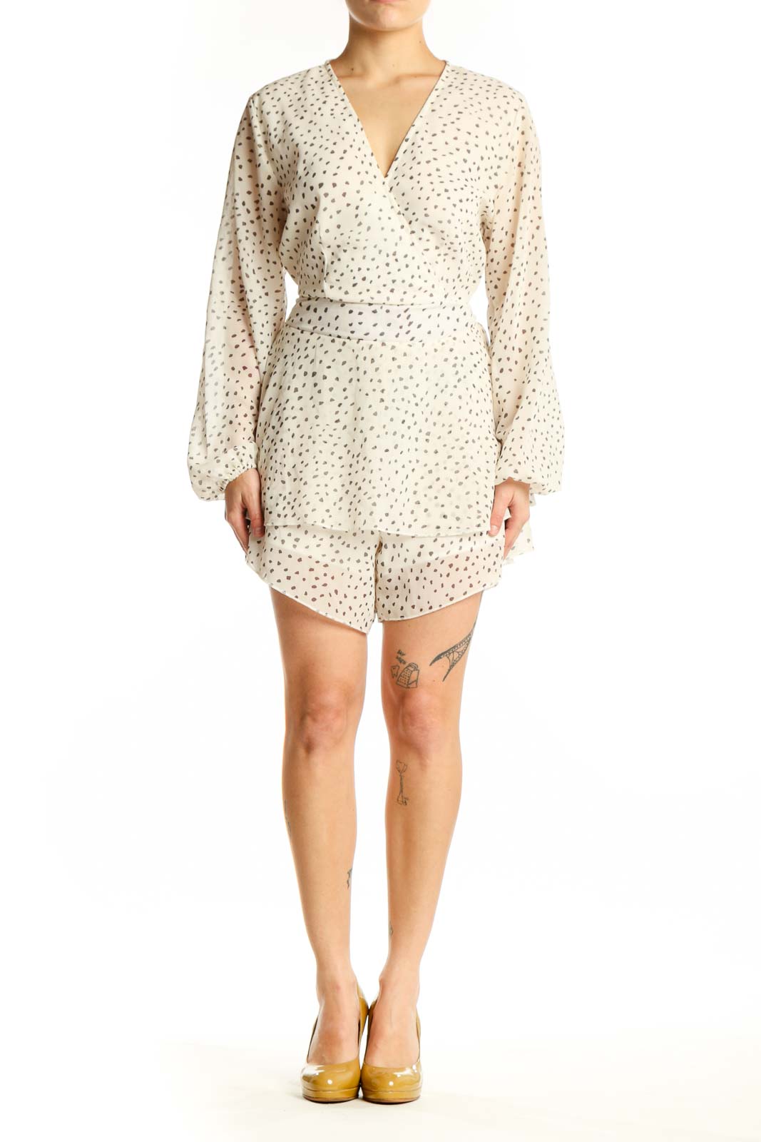 Front view of cream polka dot wrap romper with long sleeves and tiered ruffle hem