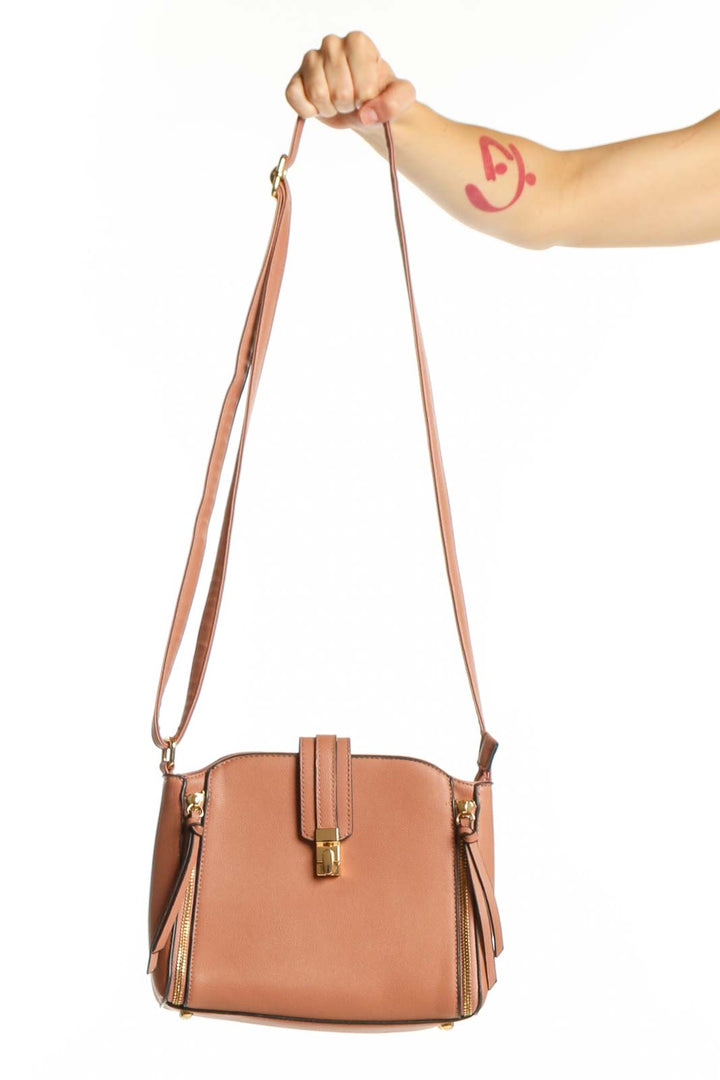 Tan structured crossbody bag with dual zip pockets and adjustable strap held by model