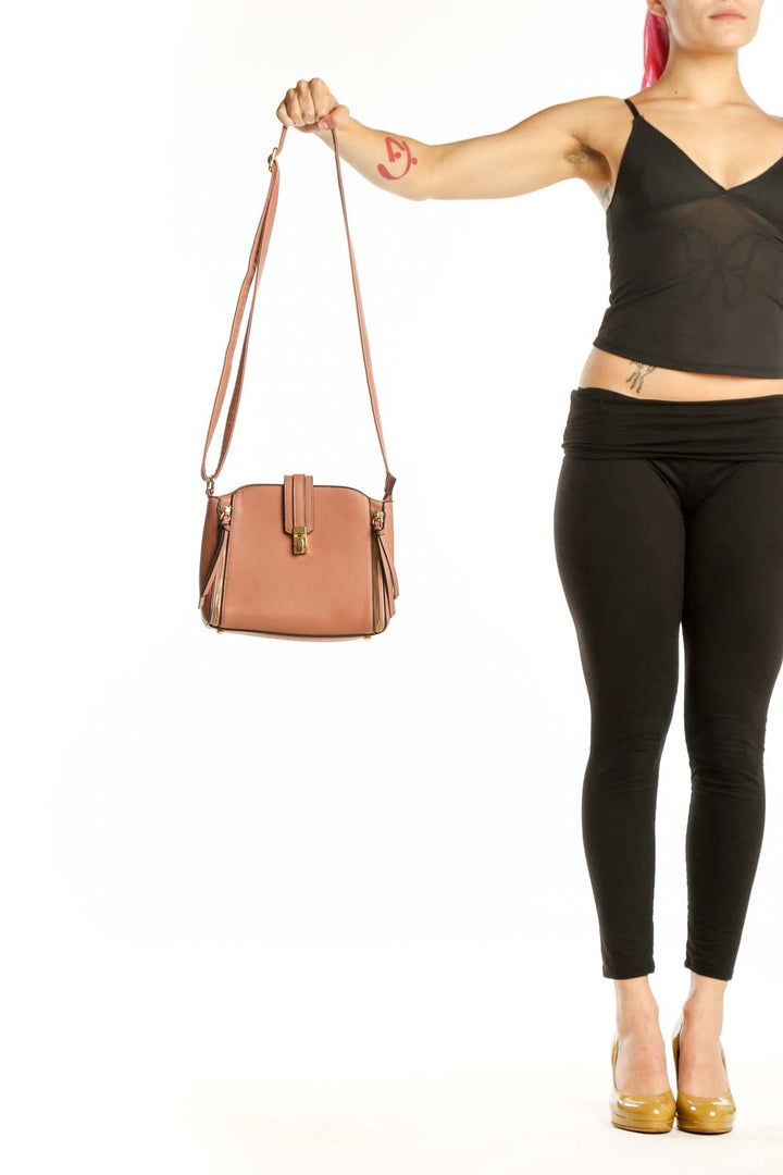 Tan structured crossbody bag with dual zip pockets and adjustable strap held by model