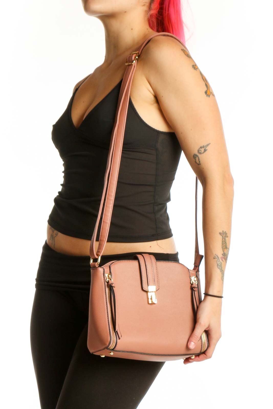Tan structured crossbody bag with dual zip pockets and adjustable strap held by model