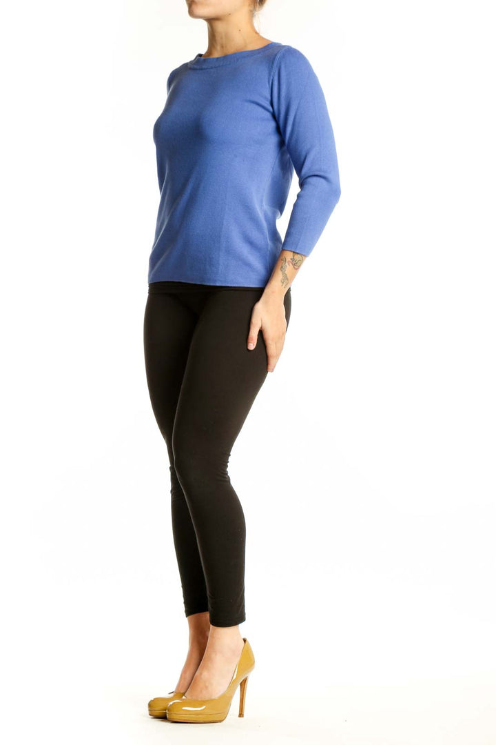 Blue crew neck top with three-quarter sleeves worn with black pants, front view