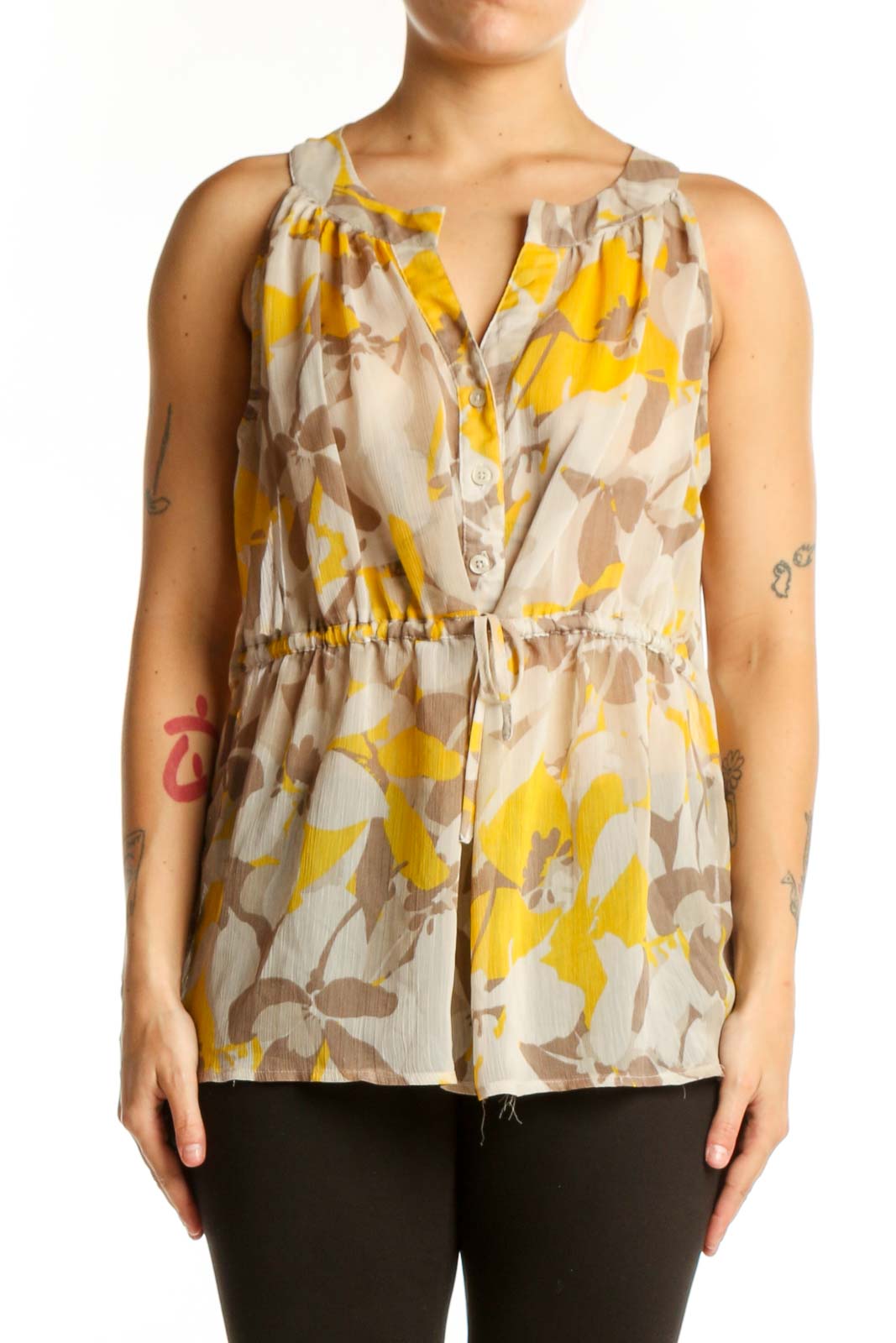Gap yellow and taupe floral sleeveless top with V-neckline and button-front closure, worn with black pants
