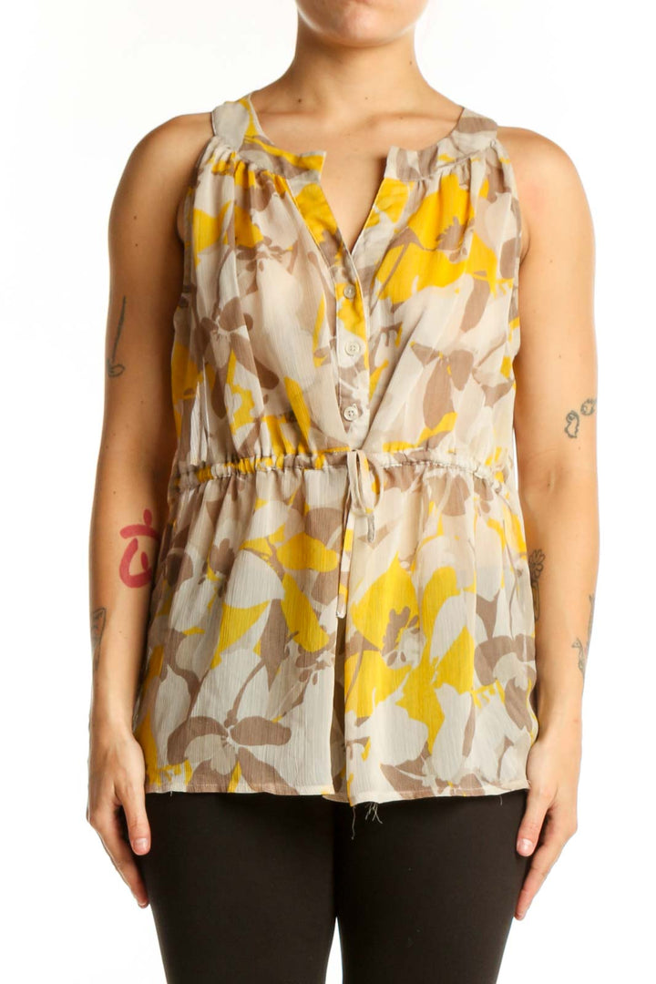 Gap yellow and taupe floral sleeveless top with V-neckline and button-front closure, worn with black pants
