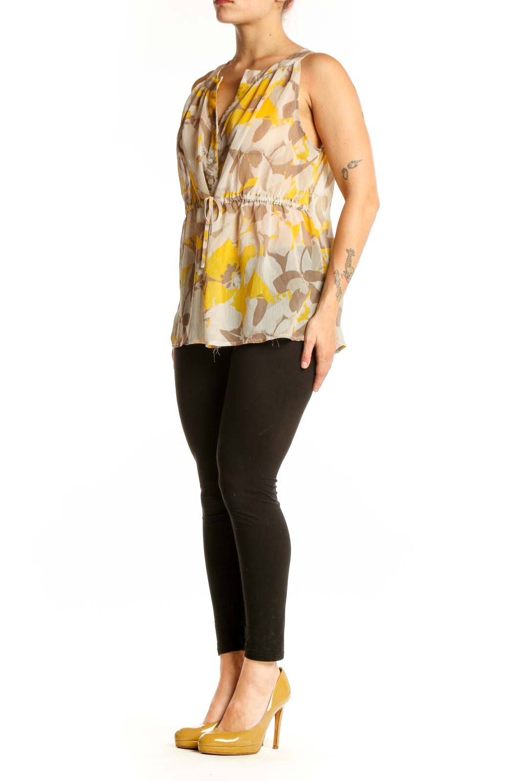 Gap yellow and taupe floral sleeveless top with V-neckline and button-front closure, worn with black pants
