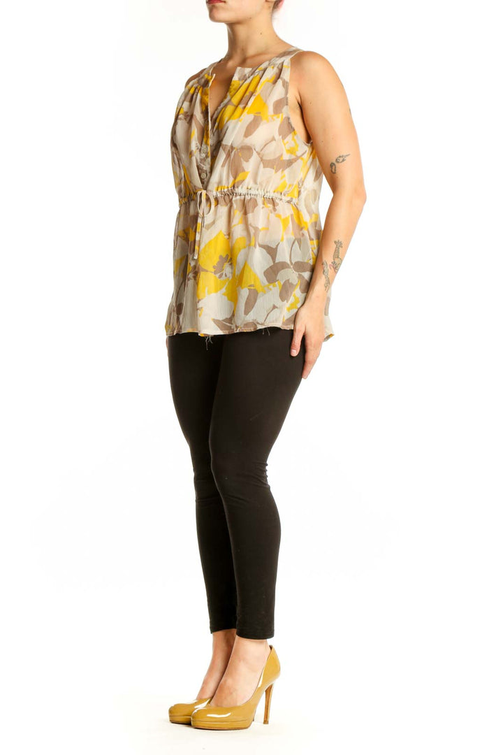 Gap yellow and taupe floral sleeveless top with V-neckline and button-front closure, worn with black pants