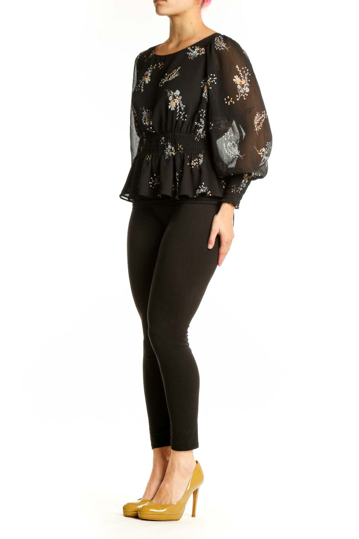 Black floral peplum blouse with sheer sleeves and gathered waist, front view