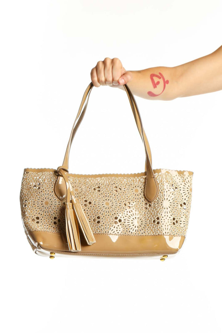 Gold BUCO shoulder bag with lace cutout design and tassel detail, held by model