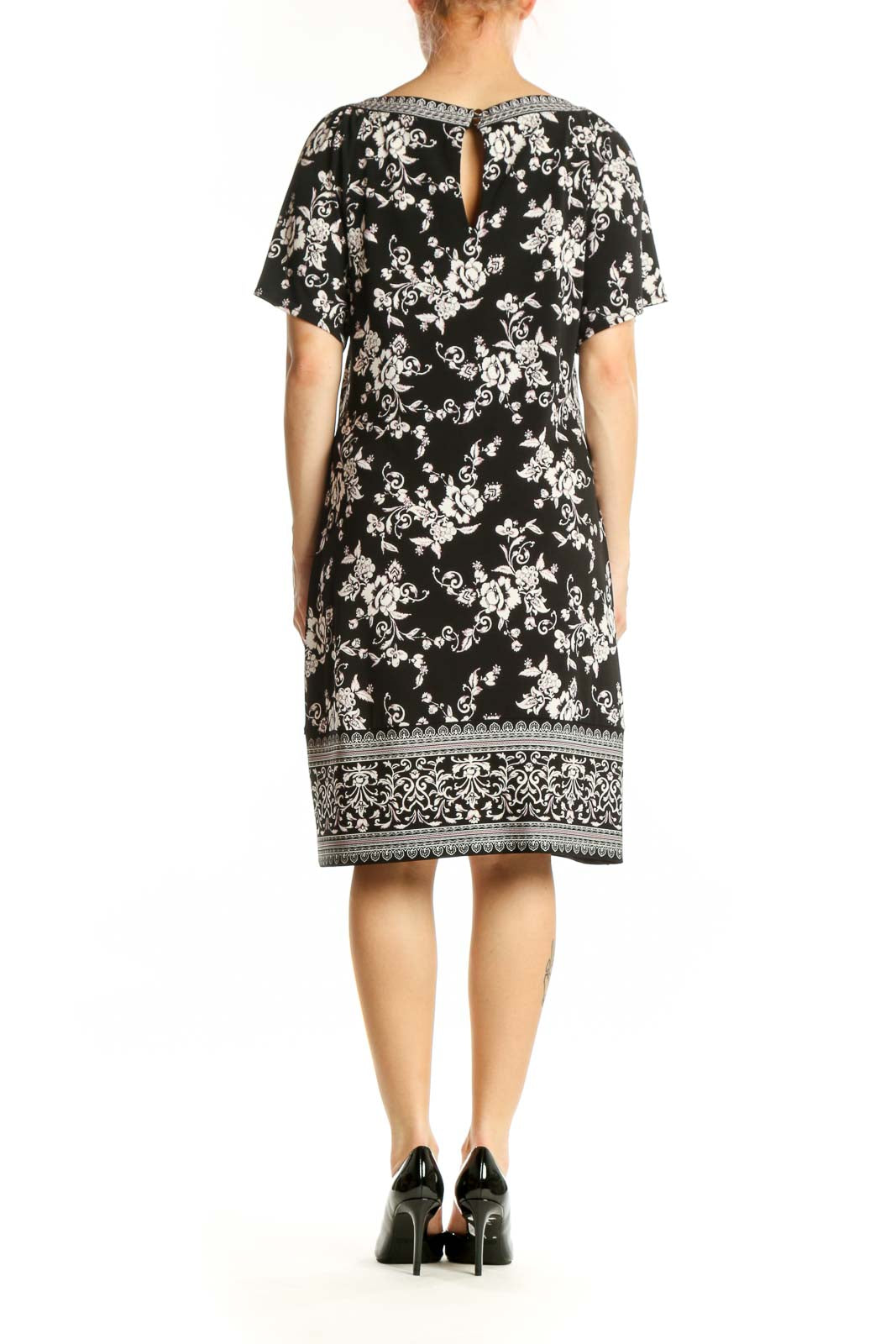 Black floral print short sleeve dress with ornate border trim, back view