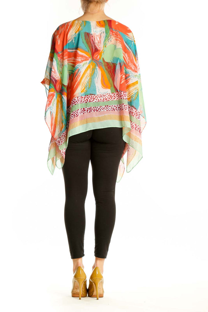 Back view of multicolor poncho top showing artistic abstract print design and geometric dot and stripe details on lower section