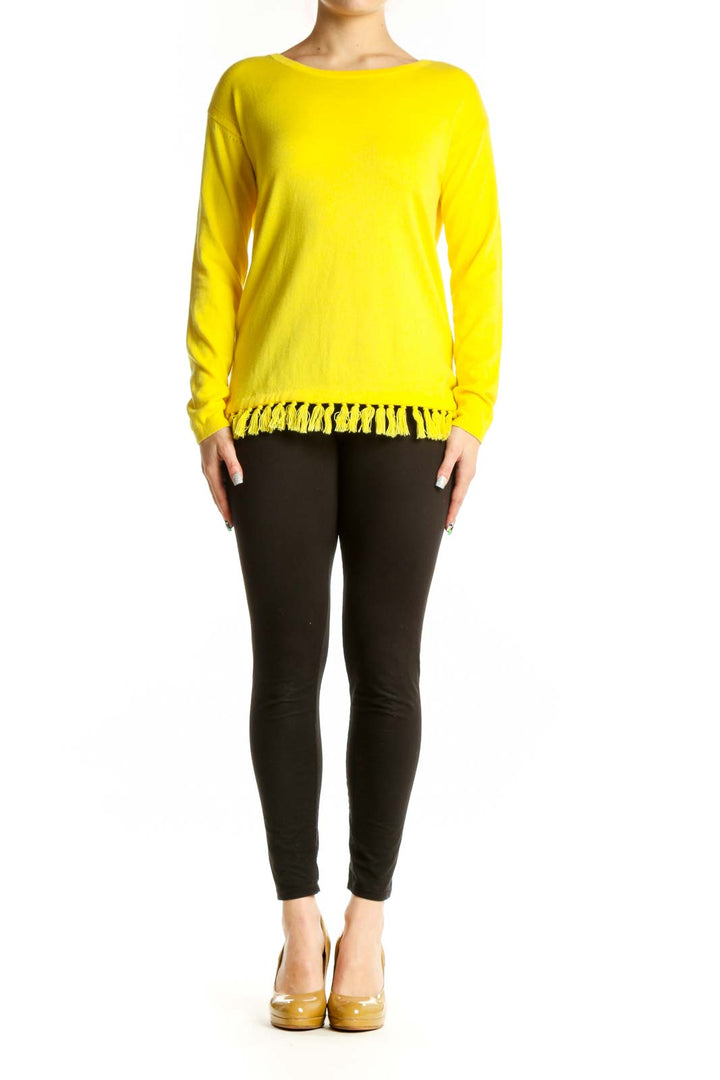 Yellow cashmere blend sweater with fringe trim worn with black pants, front view