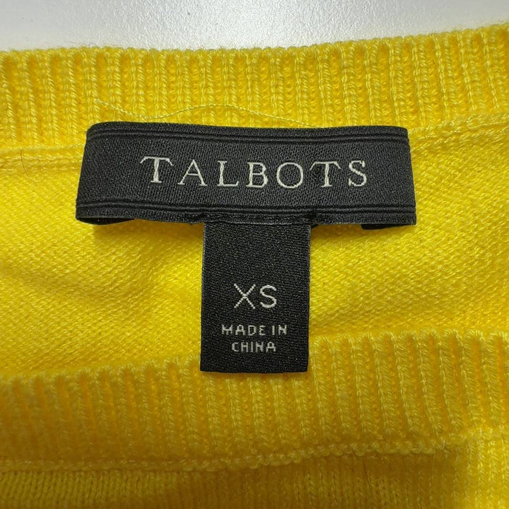 Yellow cashmere blend sweater with fringe trim worn with black pants, back view
