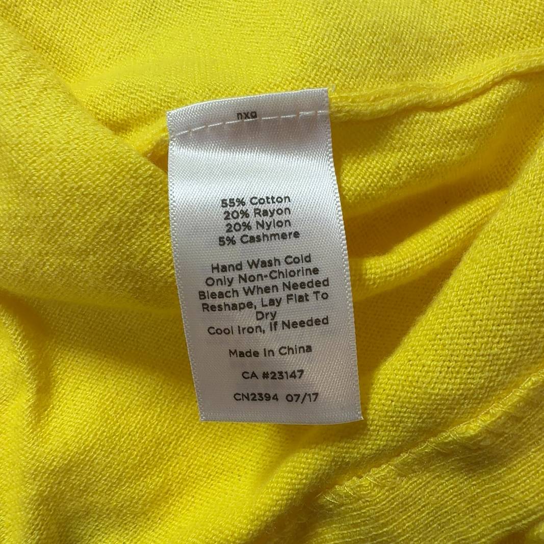 Yellow cashmere blend sweater with fringe trim worn with black pants, back view