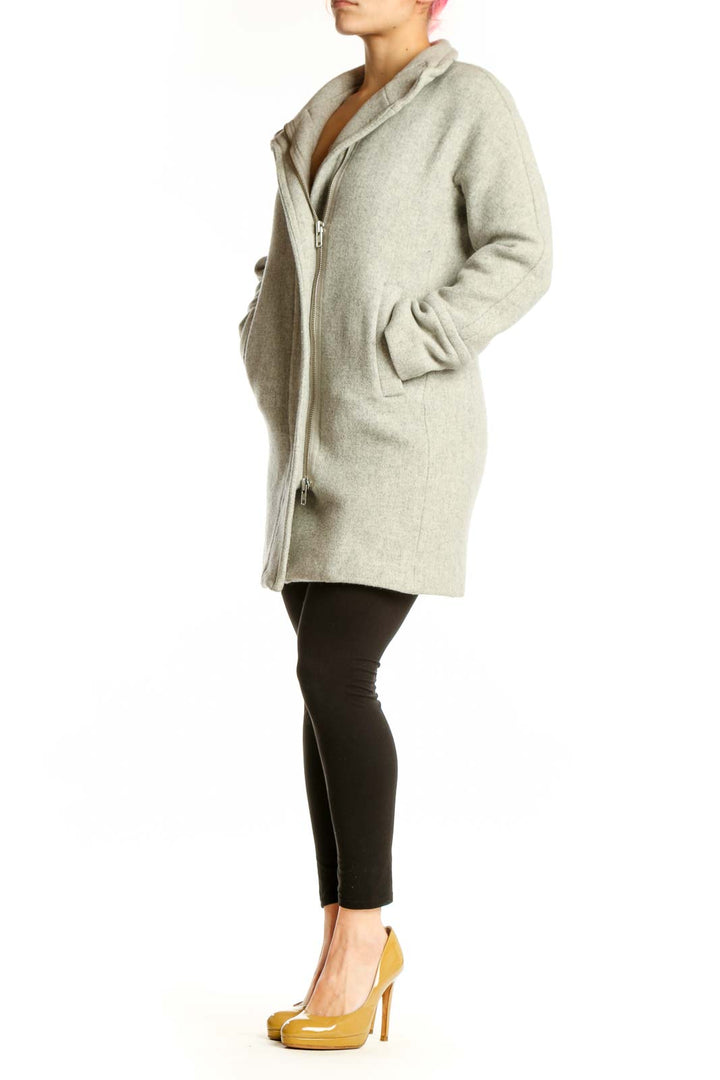 Woman wearing cream wool hooded zip-up coat with front pockets, paired with black leggings