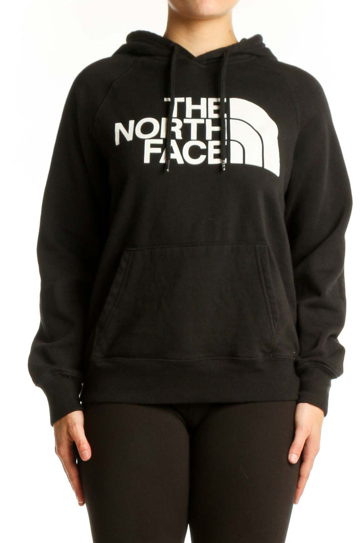 Black The North Face hoodie with white logo on front, worn by model showing kangaroo pocket and drawstring hood
